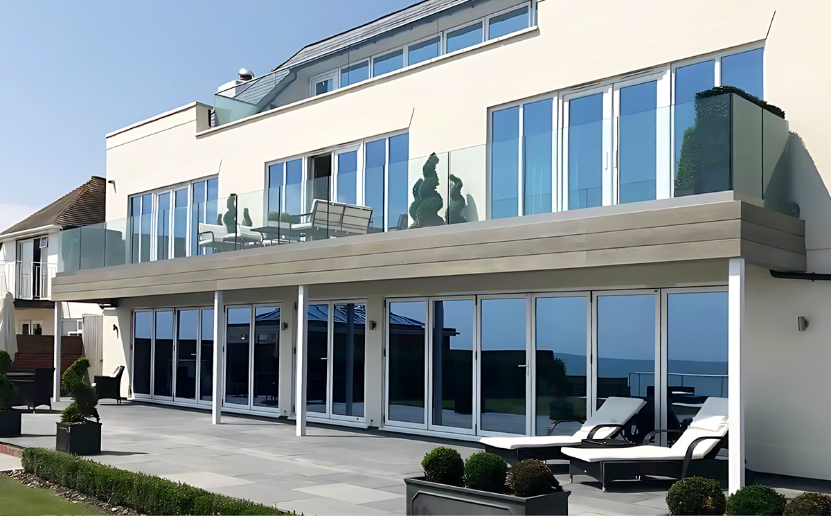 A multi-story modern seaside villa featuring custom aluminum folding doors across all patio and balcony levels