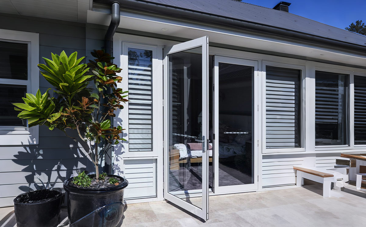 Exterior outswing French patio door open onto a backyard deck