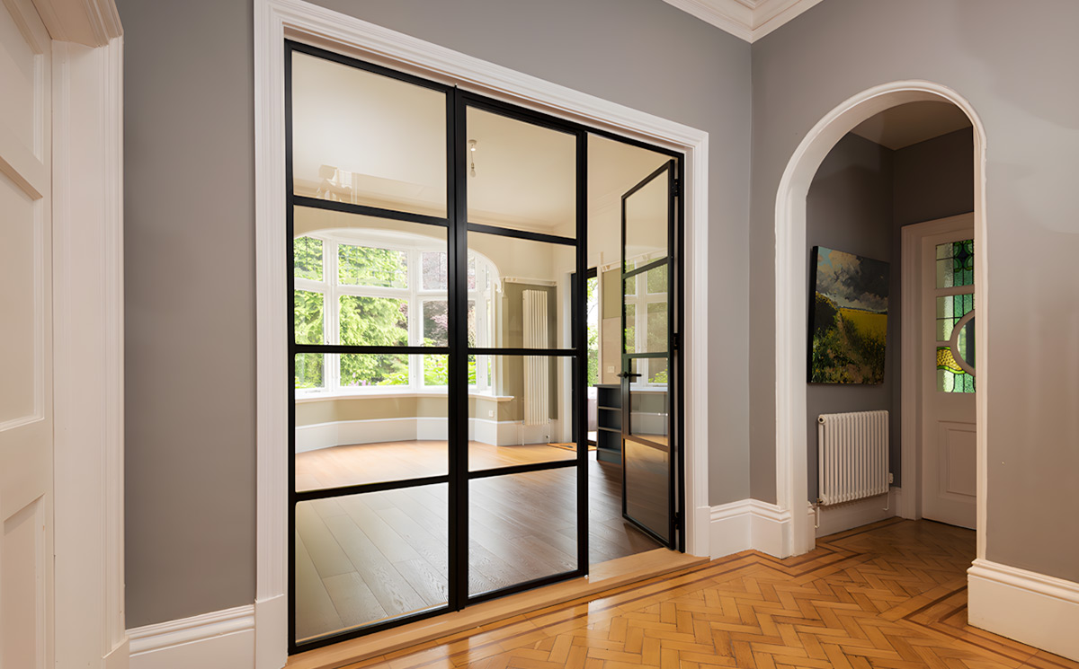 Modern interior French room divider doors with black slim frames and glass grids dividing living room and hallway