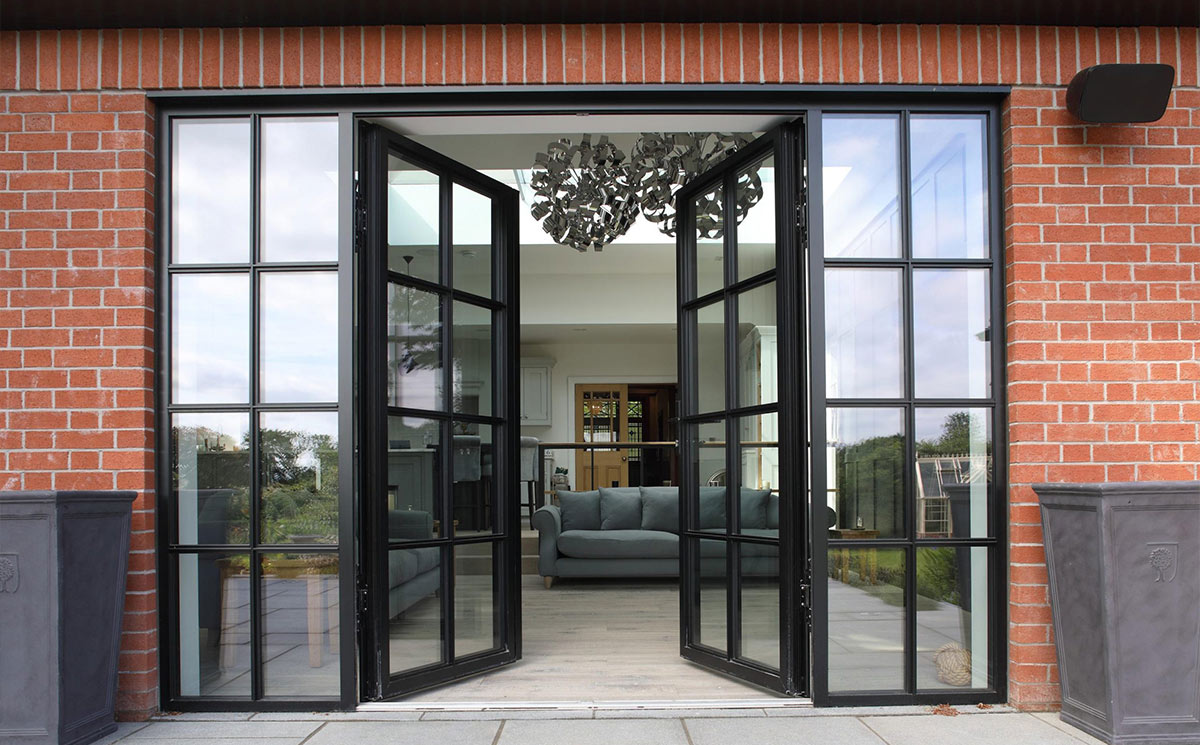 Black Crittall style double French doors with glass sidelites installed on brick exterior wall