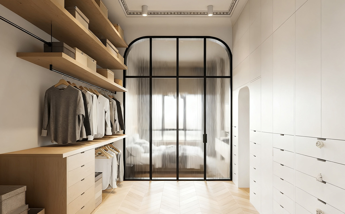 French style arched slim frame fluted reeded glass swing door partition separating a modern walk in closet from the master bedroom