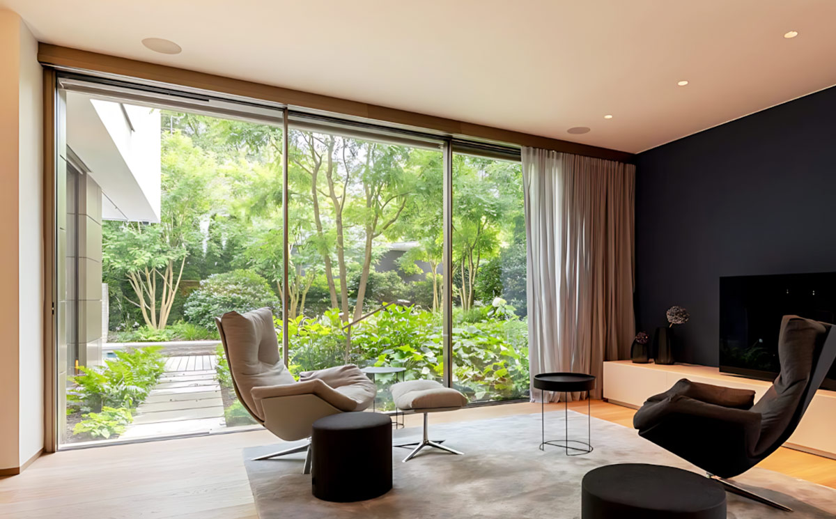 Modern living room interior with ultra slim sliding door providing uninterrupted green garden view