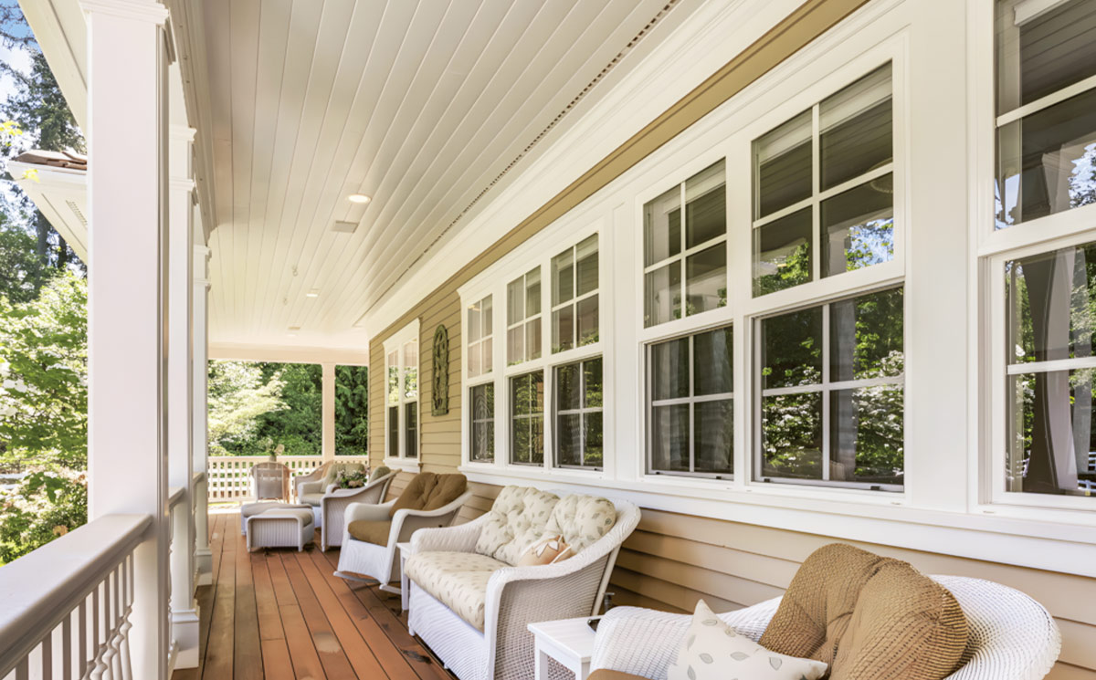 White double hung windows with grids installed along a traditional American porch terrace